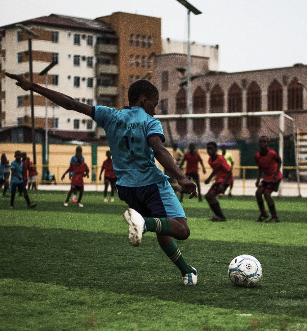 A young footballer striking the ball on a pitch
